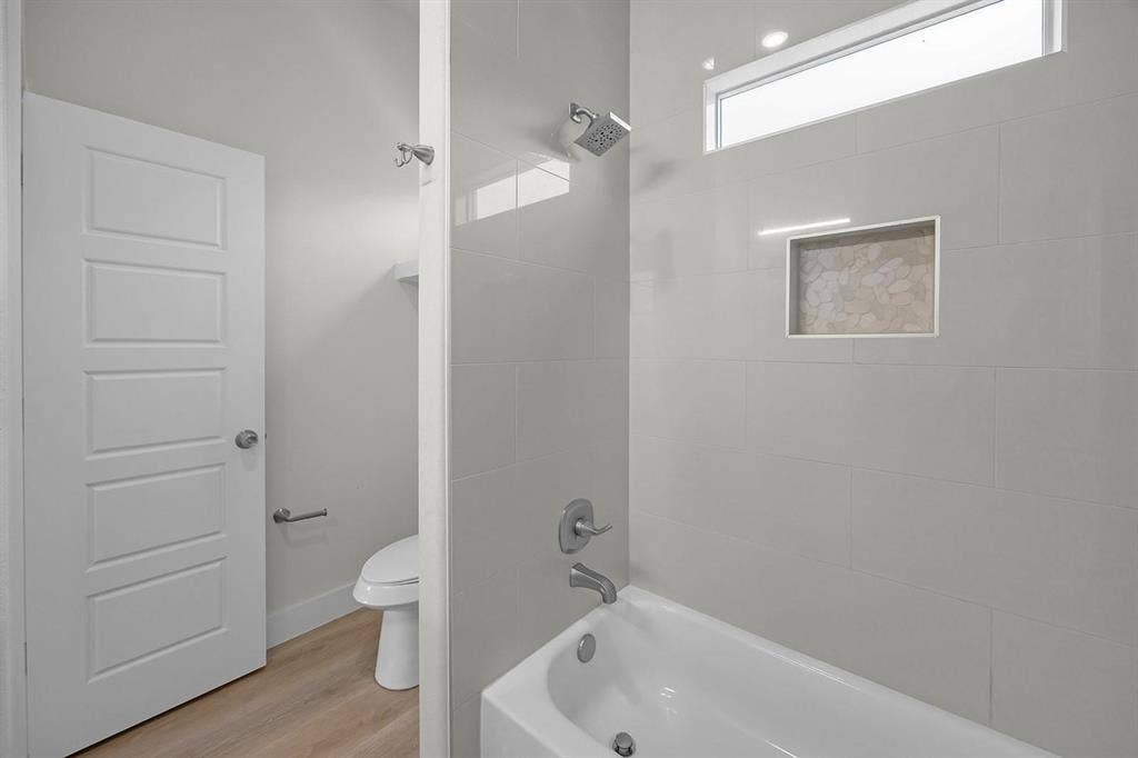 5511 Black Pine Circle, Granbury, TX 76048 Bathtub with tiled surround, wall-mounted showerhead, and integrated shower niche