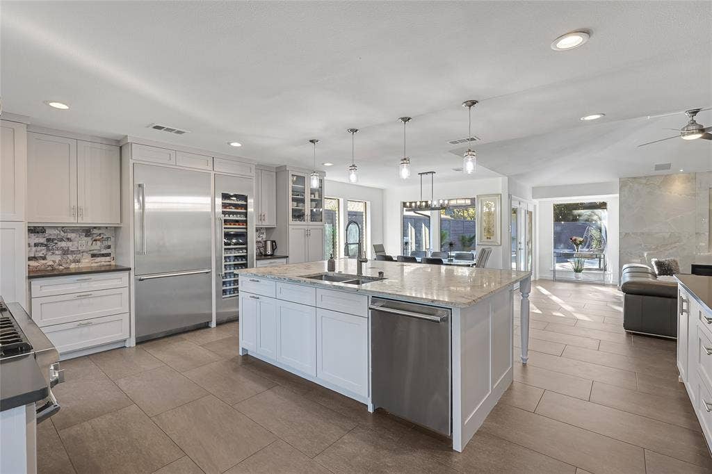 6802 Duffield Drive, Dallas, TX 75248 White cabinetry, stainless steel appliances, a large center island with a sink, recessed lighting, and tile flooring