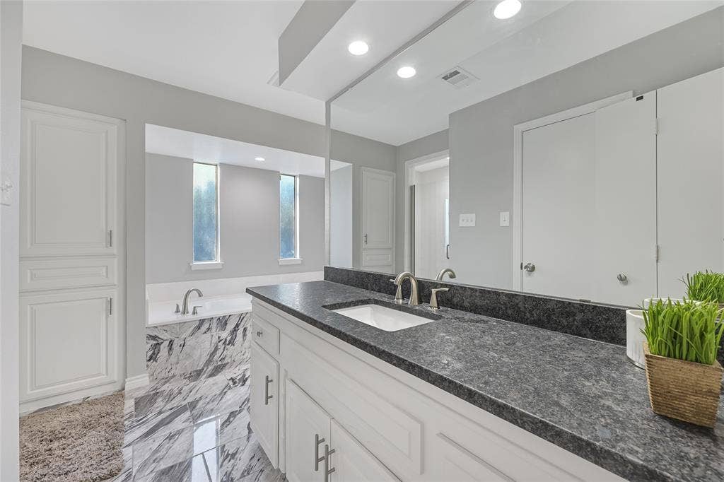 6802 Duffield Drive, Dallas, TX 75248 Dual vanity with dark stone countertops, undermount sinks, and brushed nickel fixtures