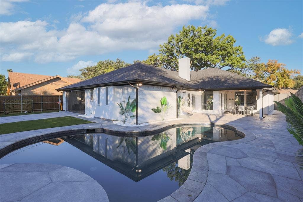 6802 Duffield Drive, Dallas, TX 75248 Resort-style backyard featuring a dark bottom swimming pool, stone patio, artificial turf area, and a white brick exterior