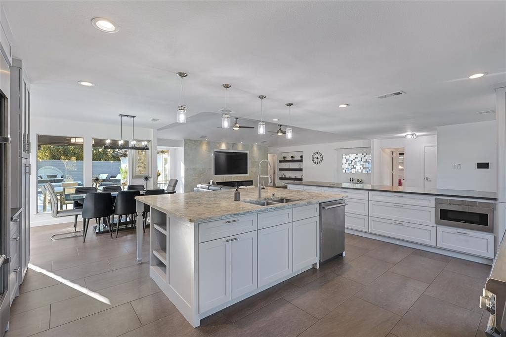 6802 Duffield Drive, Dallas, TX 75248 Expansive open-concept kitchen featuring a large central island with a double basin sink, white cabinetry, and recessed lighting