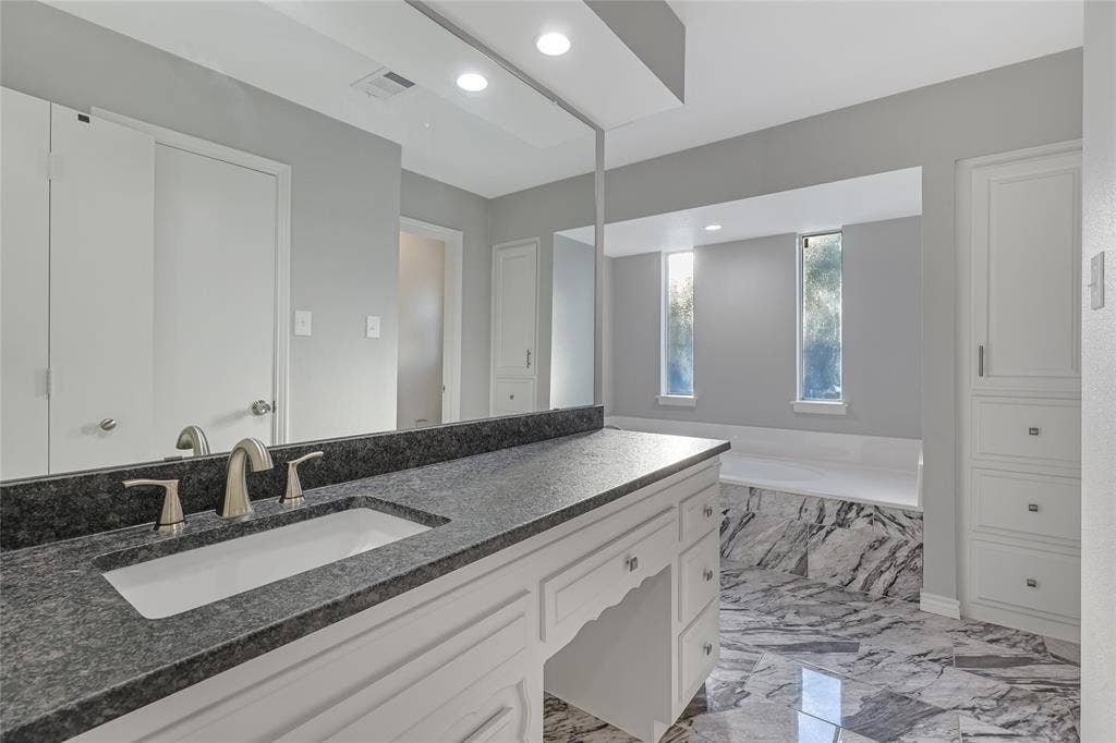 6802 Duffield Drive, Dallas, TX 75248 Vanity with dark speckled countertop, undermount sink, and brushed nickel faucet