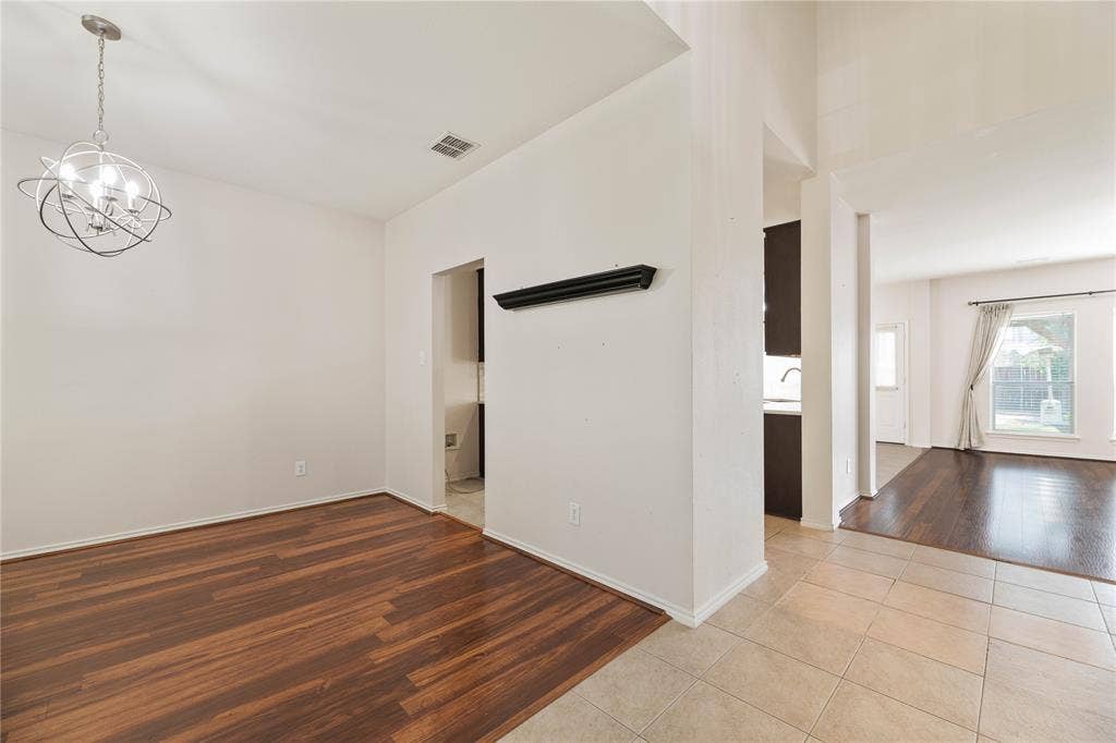 Wood-finish flooring, contemporary chandelier, tile flooring, and integrated wall shelving