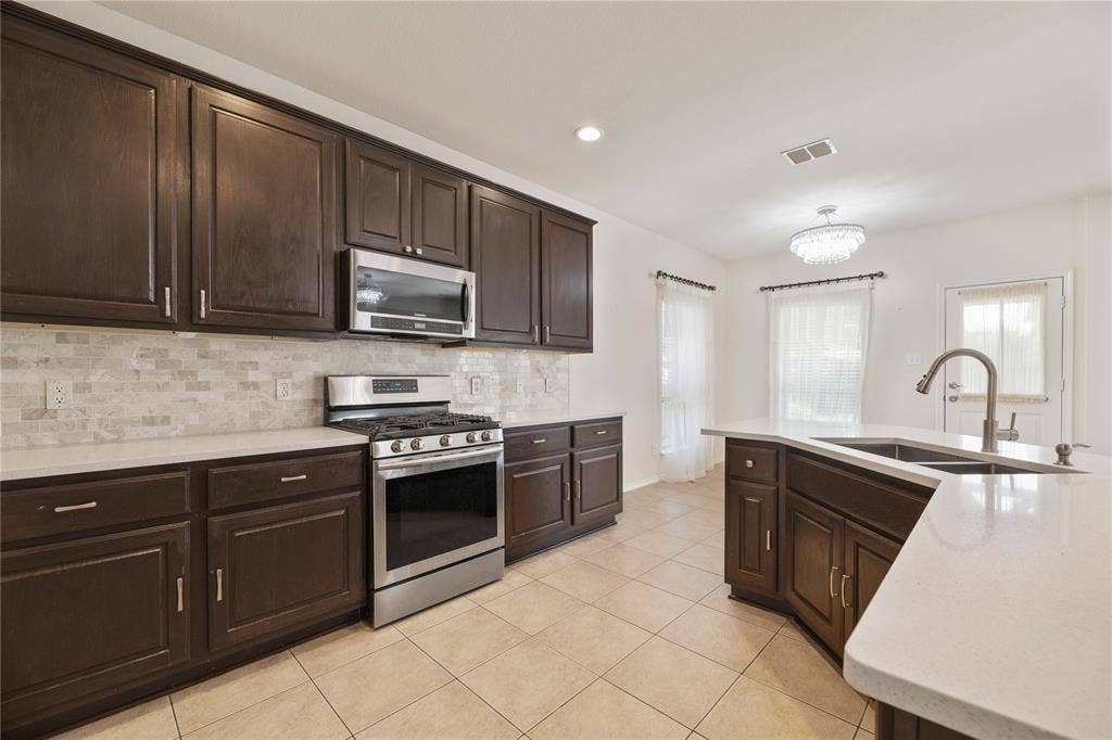 Spacious kitchen featuring dark wood cabinetry with stainless steel appliances, including a gas range and microwave