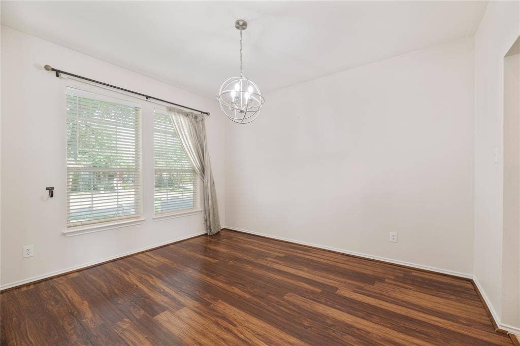 Wood-finish flooring throughout, two large windows, a contemporary spherical chandelier, and white wall finishes