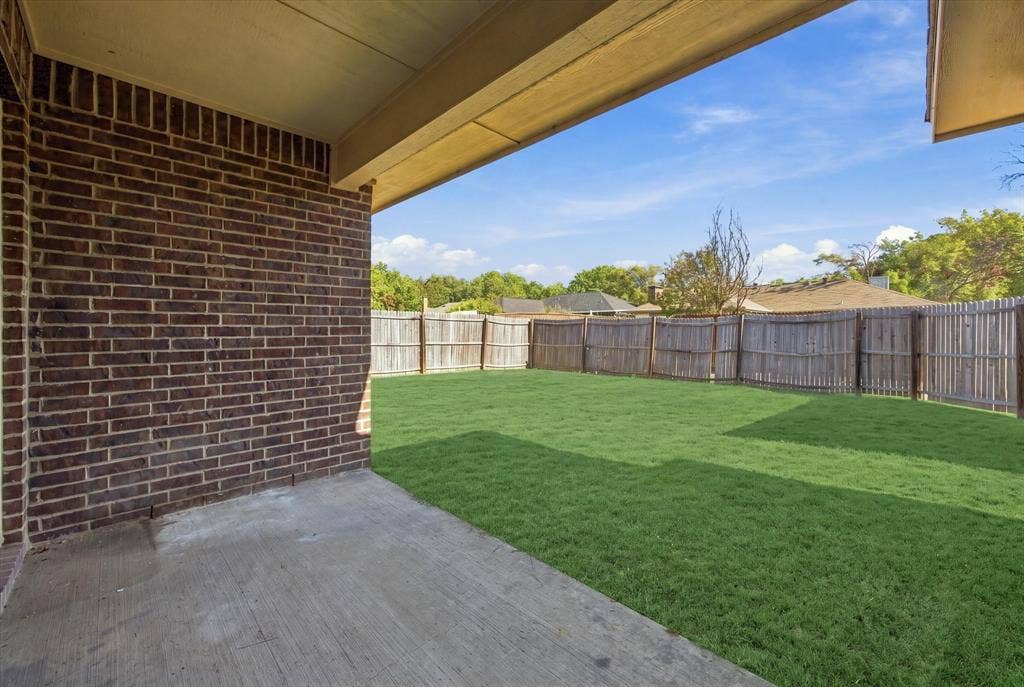 408 Northgate Drive, Terrell, TX 75160 Covered patio with a concrete surface, brick exterior wall, and wood fence enclosing a grass lawn