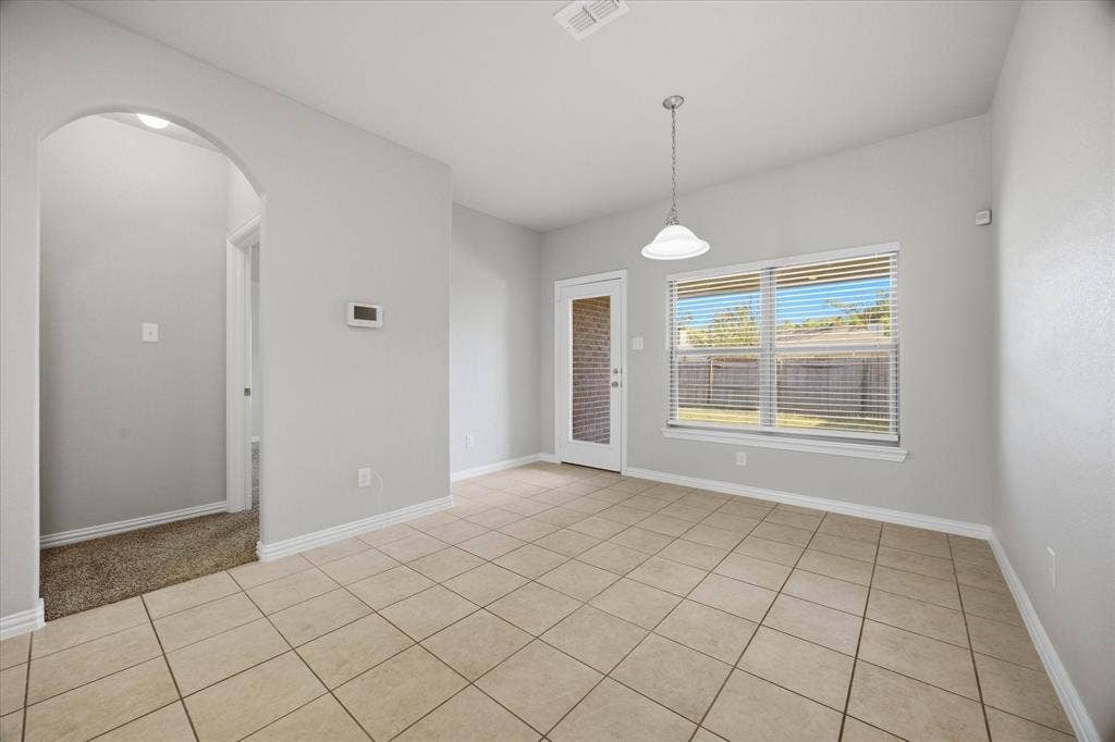 408 Northgate Drive, Terrell, TX 75160 Neutral-toned tile flooring, pendant light fixture, arched doorway, and ample natural light from exterior windows