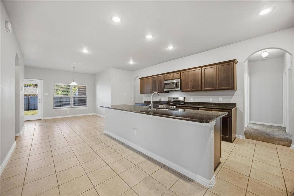408 Northgate Drive, Terrell, TX 75160 Kitchen featuring dark wood-finish cabinetry, stainless steel appliances, a center island with a sink, and dark stone-finish countertops