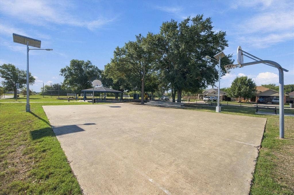 408 Northgate Drive, Terrell, TX 75160 Concrete basketball court, two basketball hoops, multiple mature trees, covered gazebo, and stadium seating