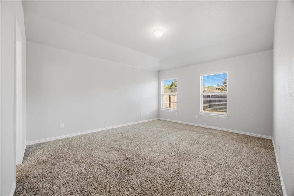 408 Northgate Drive, Terrell, TX 75160 Neutral-toned carpeting, vaulted ceiling, and two windows with blinds