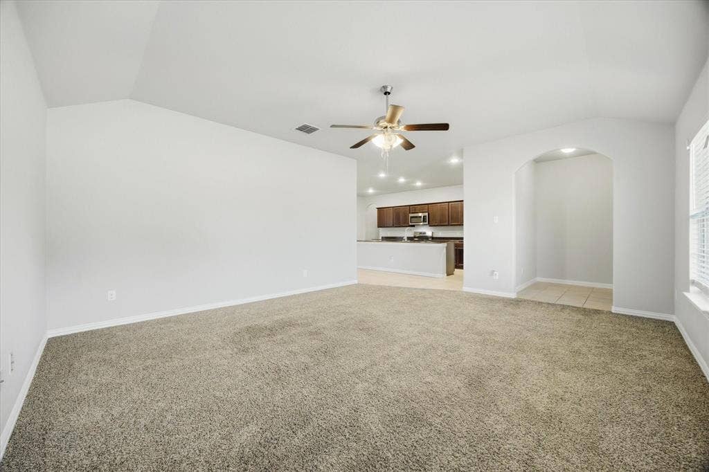 408 Northgate Drive, Terrell, TX 75160 Vaulted ceiling with a ceiling fan, carpet flooring, arched doorway, recessed lighting, and kitchen with dark wood-finish cabinetry