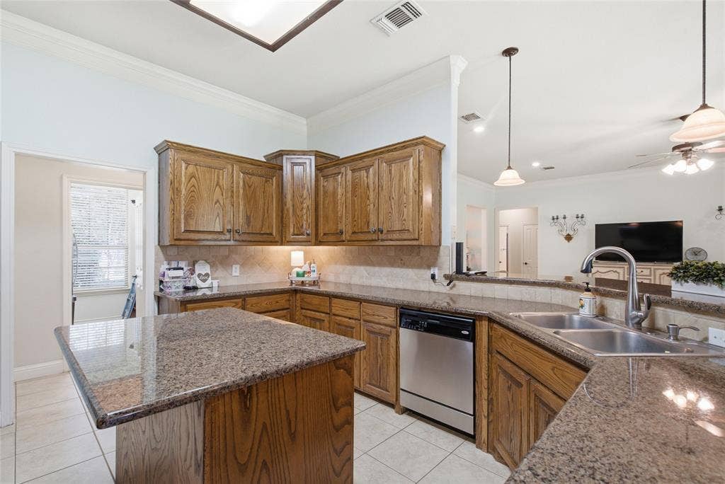 Kitchen featuring wood cabinetry, stone-surface countertops, tile flooring, a central island, and stainless steel dishwasher