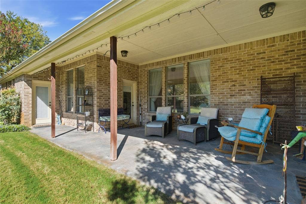 Covered patio featuring a stone floor, brick exterior wall, and wooden support columns