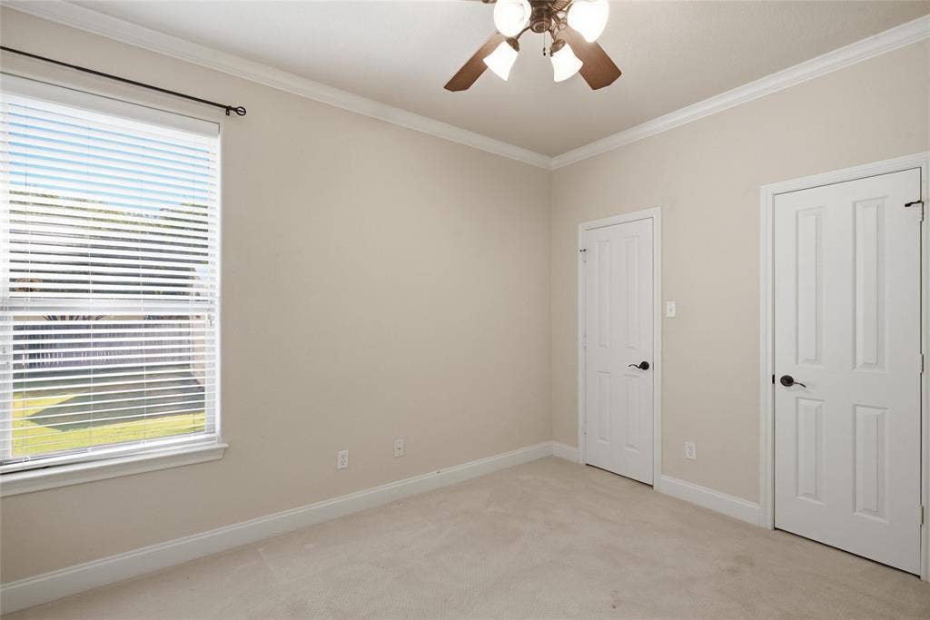 Bedroom featuring crown molding, neutral wall tones, carpeted flooring, a ceiling fan with integrated lighting, and a double-door closet