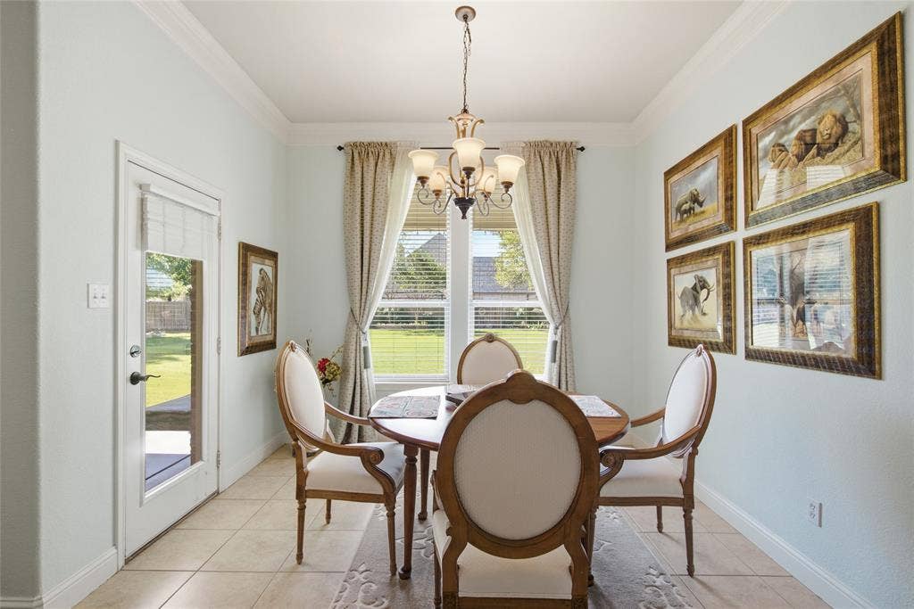 Dining space featuring ceramic tile flooring, crown molding, a multi-arm chandelier, and a glass-paneled exterior door