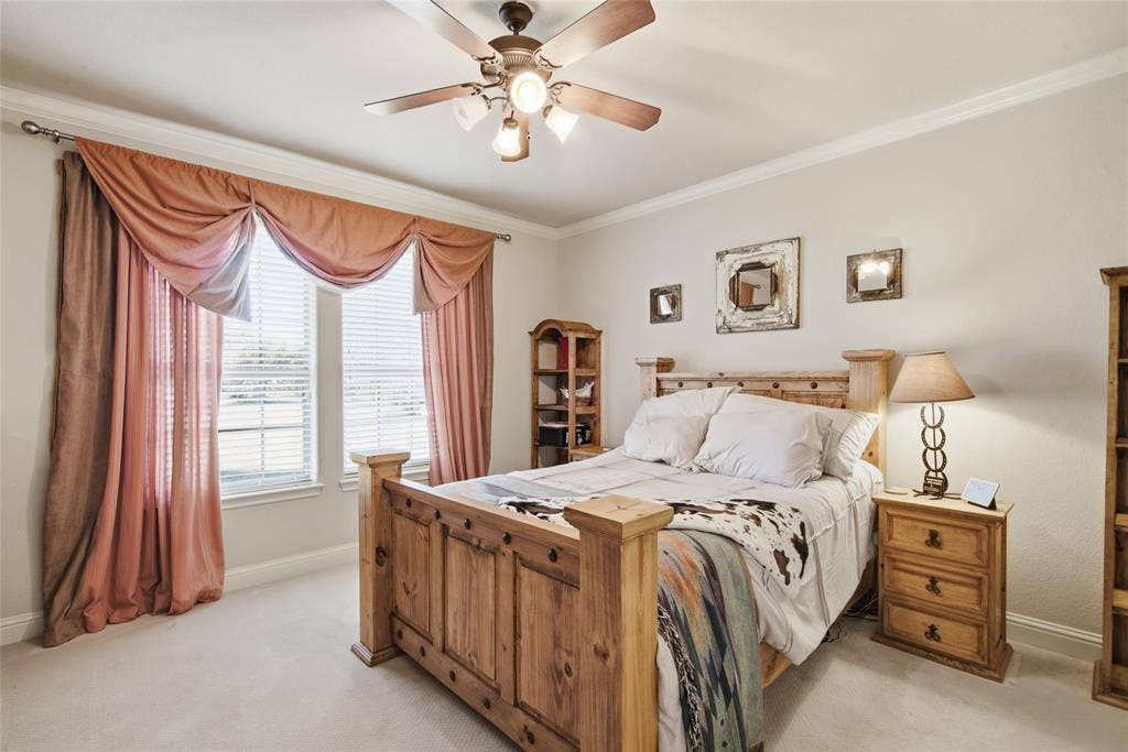 Room featuring neutral wall tones, crown molding, wall-to-wall carpeting, a multi-light ceiling fan, and two interior doors with matte black hardware