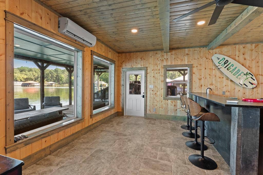 18630 Eastside Road, Troup, TX 75789 Wood-paneled interior with exposed beam ceiling, large windows, and a built-in bar