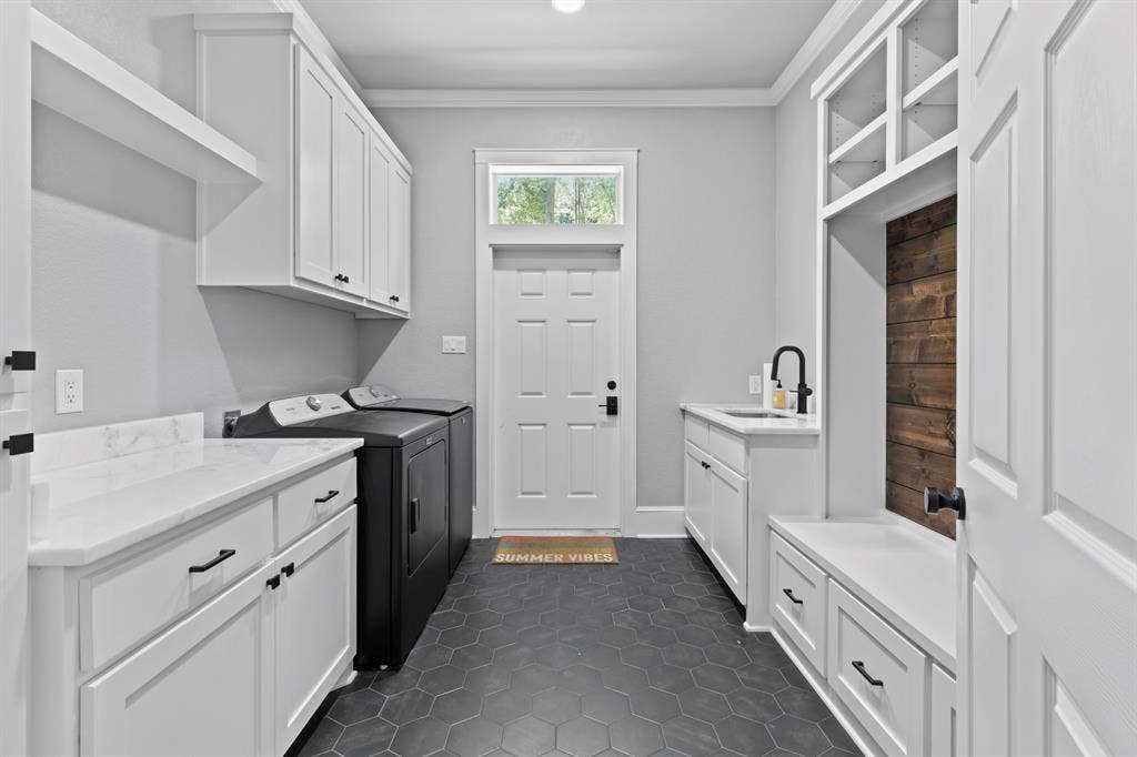 18630 Eastside Road, Troup, TX 75789 White shaker cabinetry with black hardware, white countertops, built-in mudroom bench with storage, black hexagonal floor tile, and a single basin sink with a black faucet