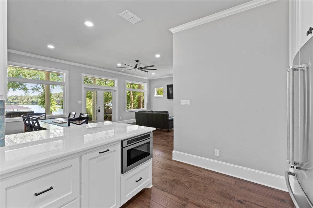 18630 Eastside Road, Troup, TX 75789 Open-concept living space featuring a white kitchen island with an integrated microwave, wood-finish flooring, and crown molding
