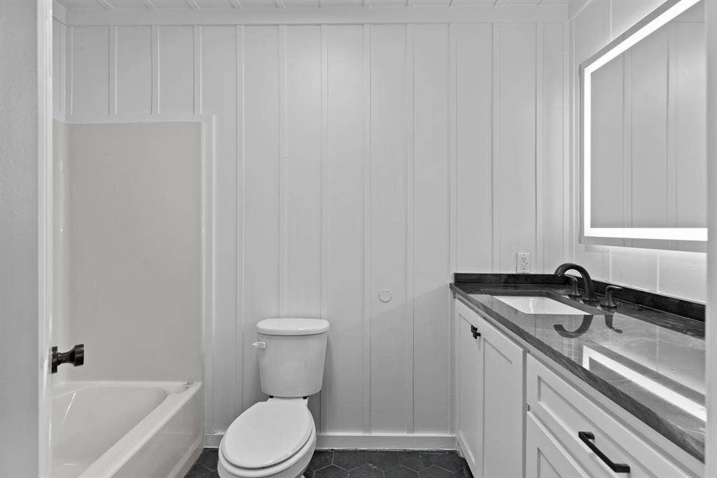 18630 Eastside Road, Troup, TX 75789 White board and batten walls, dark hexagonal floor tiling, and a white vanity with a dark countertop