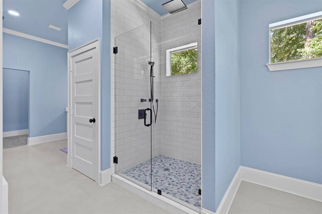 18630 Eastside Road, Troup, TX 75789 Glass-enclosed shower featuring subway tile walls, a patterned tile floor, and a matte black rainfall showerhead