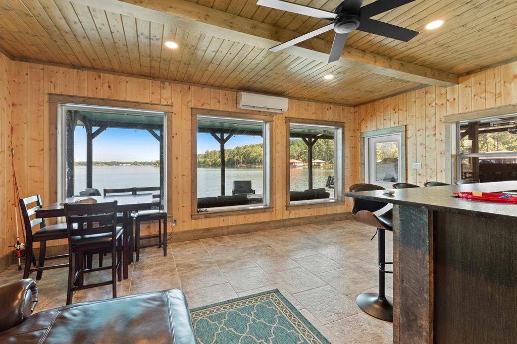 18630 Eastside Road, Troup, TX 75789 Wood-paneled room with multiple large windows overlooking a body of water