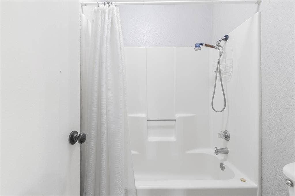 5010 Utah Street, Greenville, TX 75402 White shower-over-tub combination with a showerhead and separate handheld sprayer