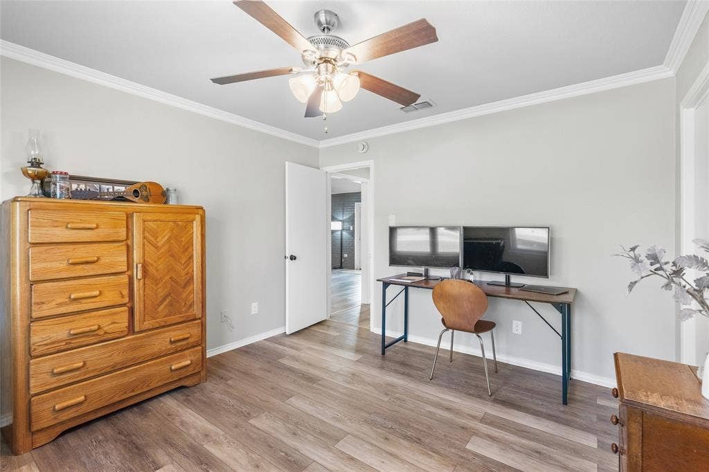 5010 Utah Street, Greenville, TX 75402 Wood-finish flooring, light gray wall paint, white trim, ceiling fan with light kit, and a white interior door