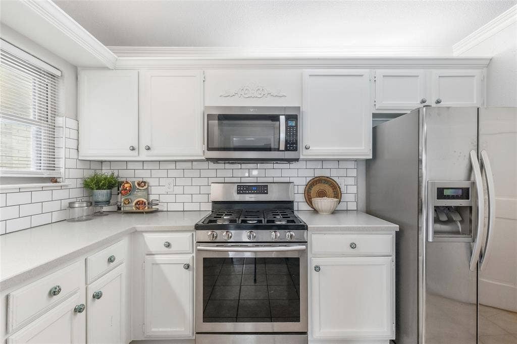 5010 Utah Street, Greenville, TX 75402 White shaker-style cabinetry, subway tile backsplash, stainless steel appliances, gas range, and extensive countertop space