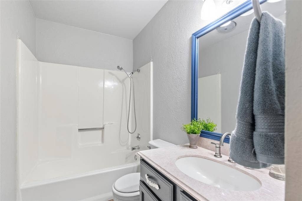 5010 Utah Street, Greenville, TX 75402 Bathroom featuring a white shower/tub combination, vanity with a built-in sink, and a framed mirror