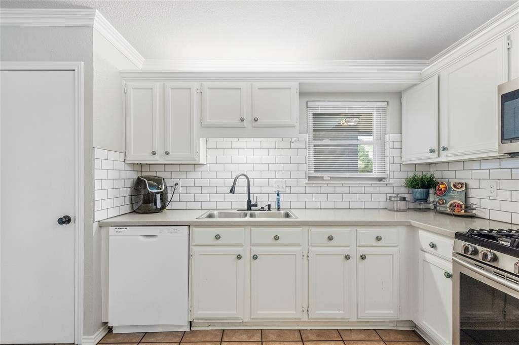 5010 Utah Street, Greenville, TX 75402 White cabinetry, subway tile backsplash, stainless steel sink, pull-down faucet, and durable countertops