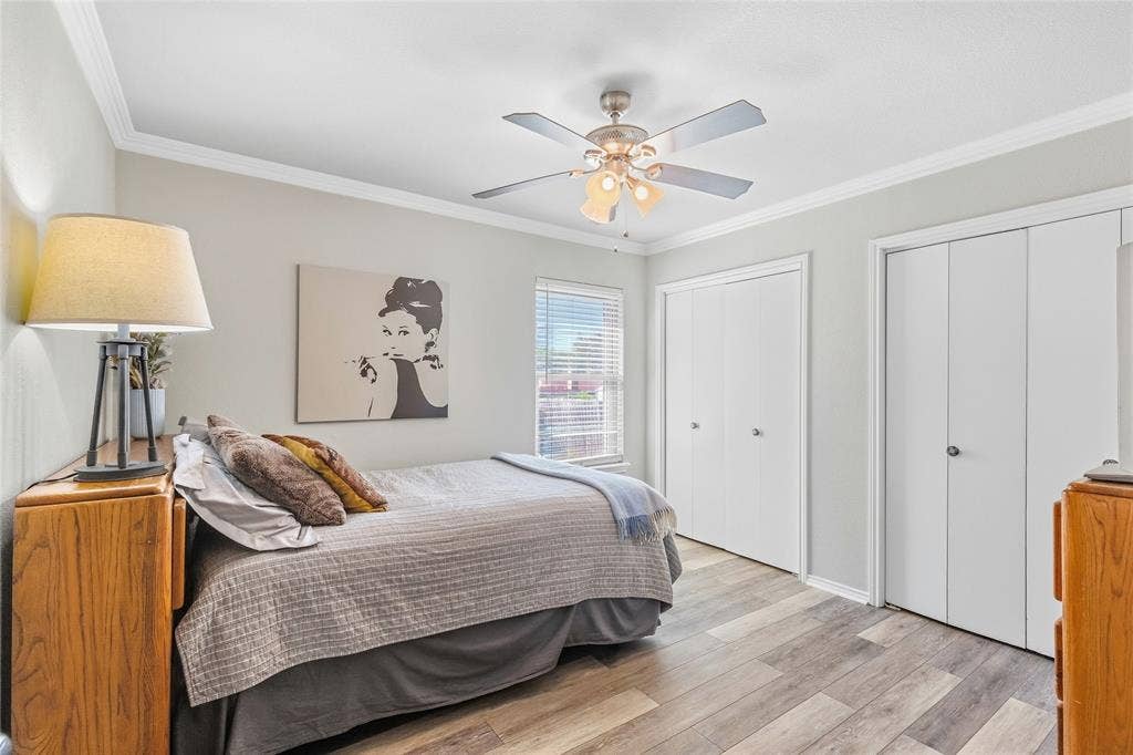 5010 Utah Street, Greenville, TX 75402 Light gray wall color, wood-finish flooring, two closet systems with white doors, ceiling fan with integrated lighting, and window with blinds