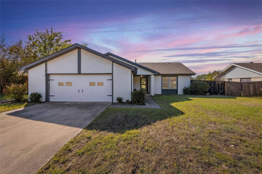 5010 Utah Street, Greenville, TX 75402 White brick exterior, dark trim accents, attached garage with decorative hardware, concrete driveway, and front entry walkway