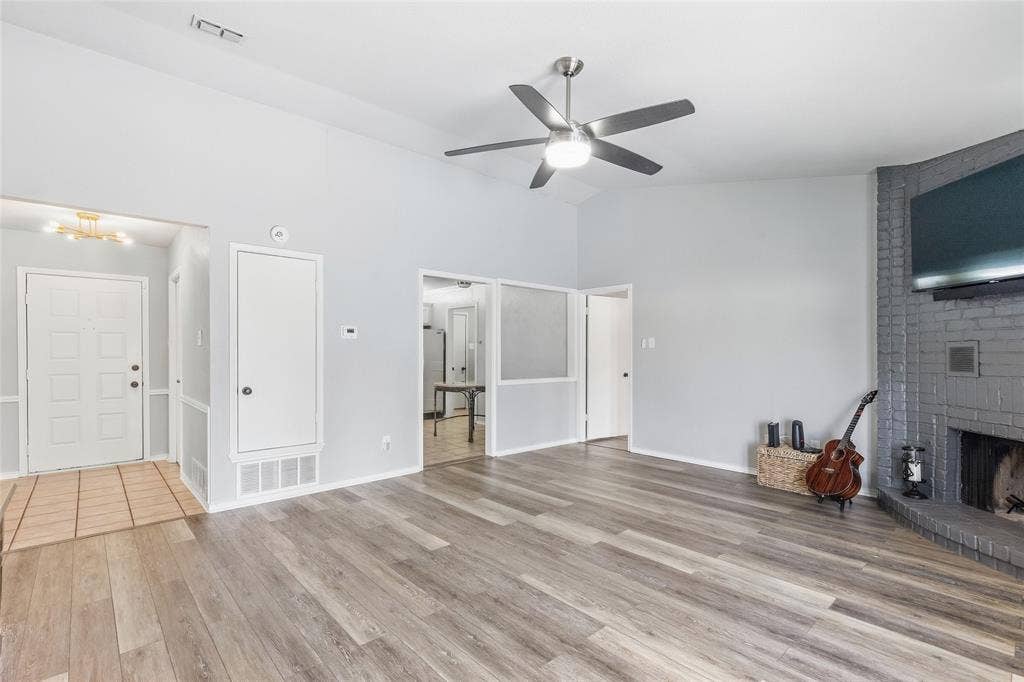 5010 Utah Street, Greenville, TX 75402 Vaulted ceiling with a ceiling fan, wood-finish flooring, brick fireplace, and a tiled entryway