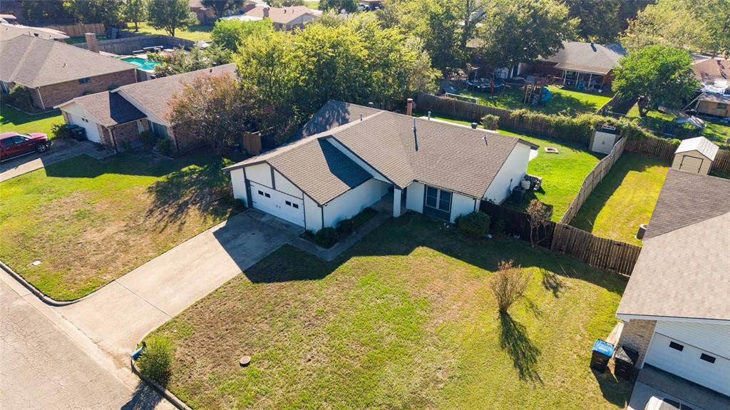 5010 Utah Street, Greenville, TX 75402 Single-story residence featuring a two-car garage, pitched roof, and a fenced backyard