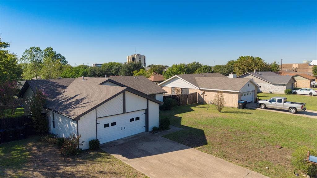 5010 Utah Street, Greenville, TX 75402 Expansive concrete driveway, white exterior siding, brown trim accents, attached two-car garage, and a lush green lawn