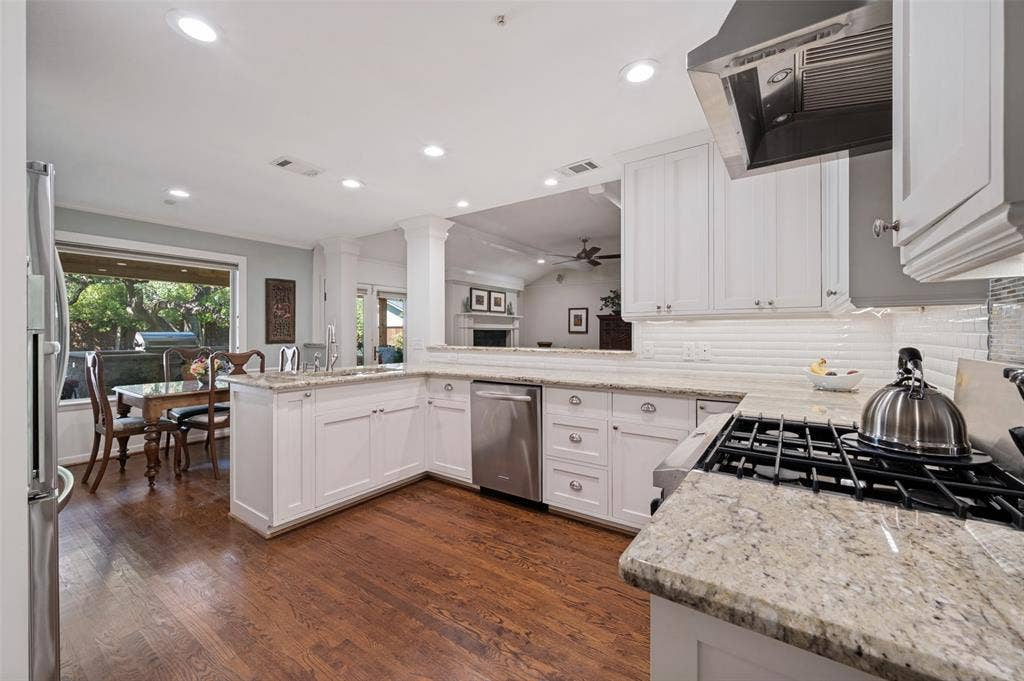 4521 Nashwood Lane, Dallas, TX 75244 Wood-finish flooring, white cabinetry, integrated stainless steel appliances, granite countertops, and recessed lighting