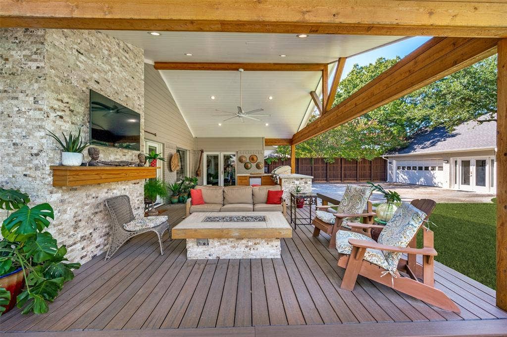 4521 Nashwood Lane, Dallas, TX 75244 Covered outdoor living space featuring vaulted ceilings, exposed wood beams, a stone-clad fireplace, and an integrated outdoor kitchen