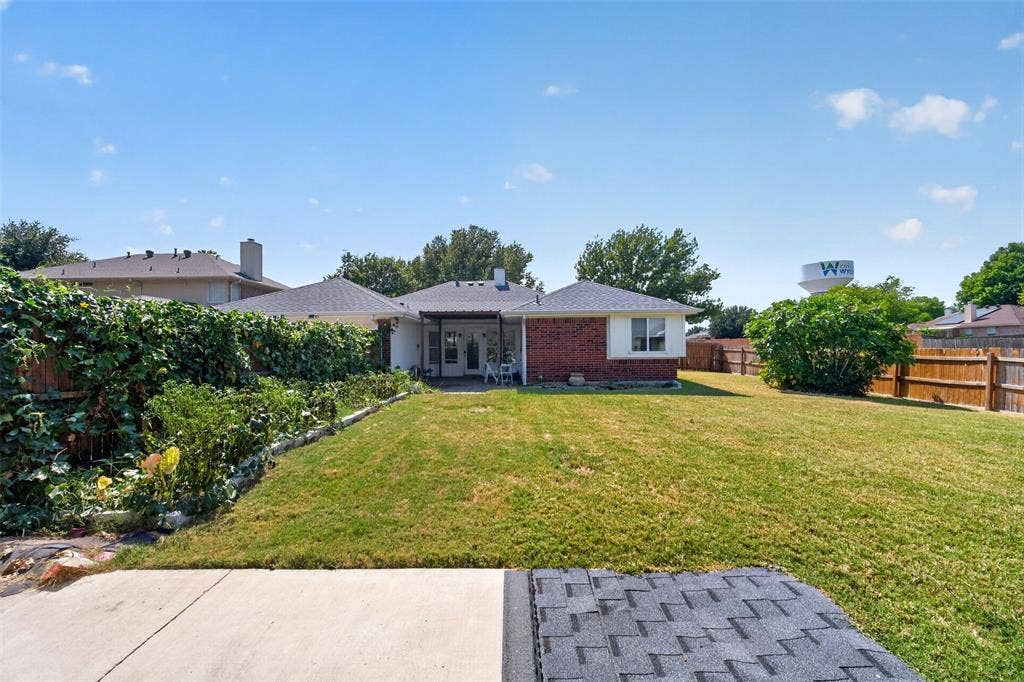 1101 Boyd Drive, Wylie, TX 75098 Expansive backyard featuring a lush lawn, mature perimeter landscaping, wood fencing, and a covered patio with white columns