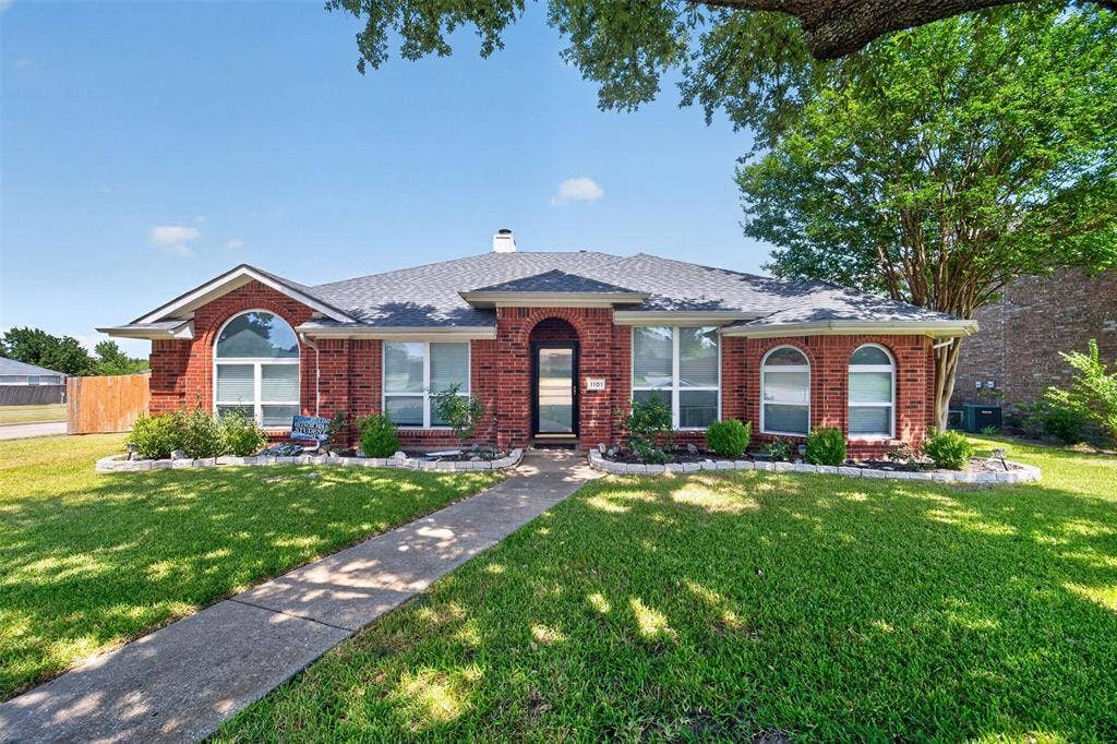 1101 Boyd Drive, Wylie, TX 75098 Red brick exterior with white trim, arched windows, and a dark shingle roof