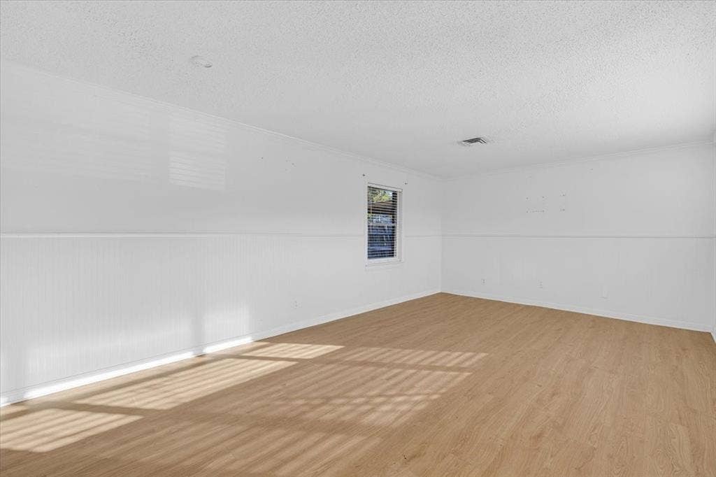 13521 Flagstone Lane, Dallas, TX 75240 Wood-finish flooring, white walls, horizontal wall paneling, and a single window with blinds