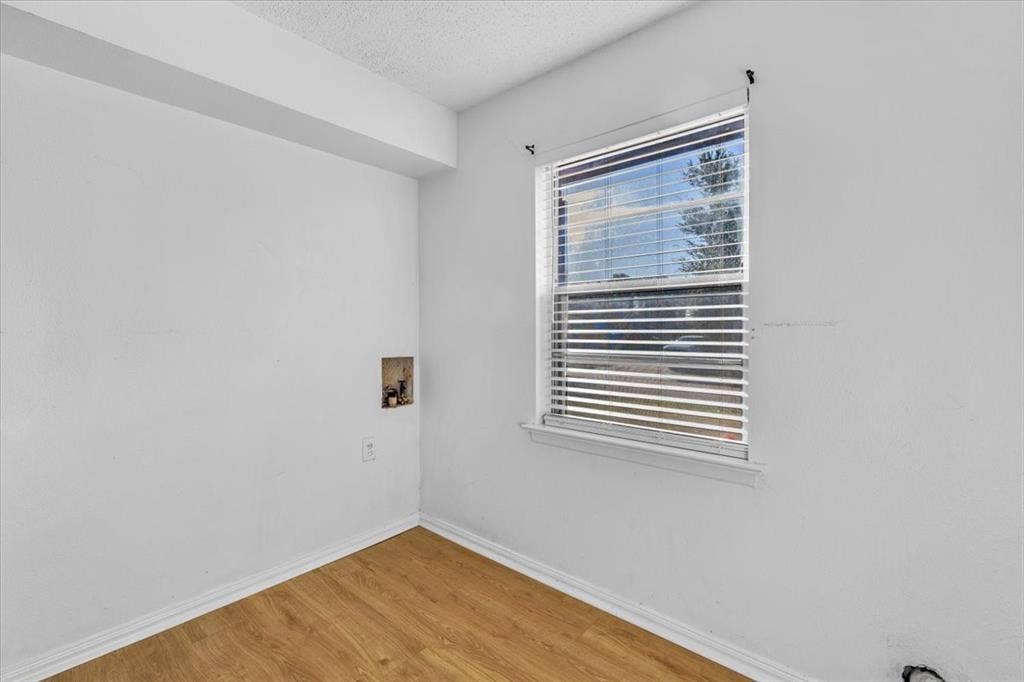 13521 Flagstone Lane, Dallas, TX 75240 Wood-finish flooring with white baseboards, a window with horizontal blinds, and a utility hookup recess