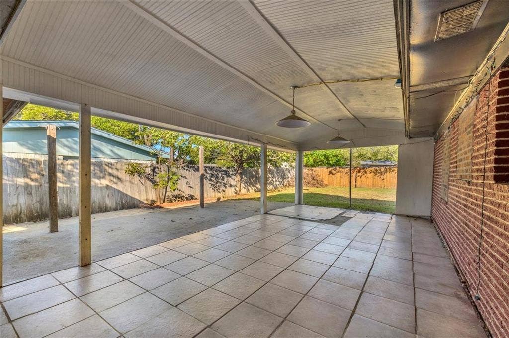 13521 Flagstone Lane, Dallas, TX 75240 Covered patio with durable tile flooring and exposed brick wall