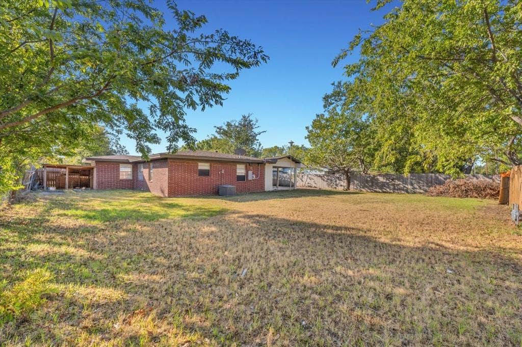 13521 Flagstone Lane, Dallas, TX 75240 Expansive backyard with a brick exterior, covered patio, and mature trees