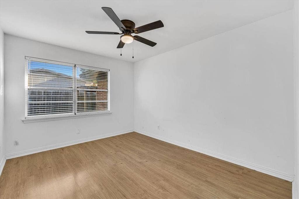 13521 Flagstone Lane, Dallas, TX 75240 Wood-finish flooring, white walls, white trim, window with blinds, and a ceiling fan with light fixture