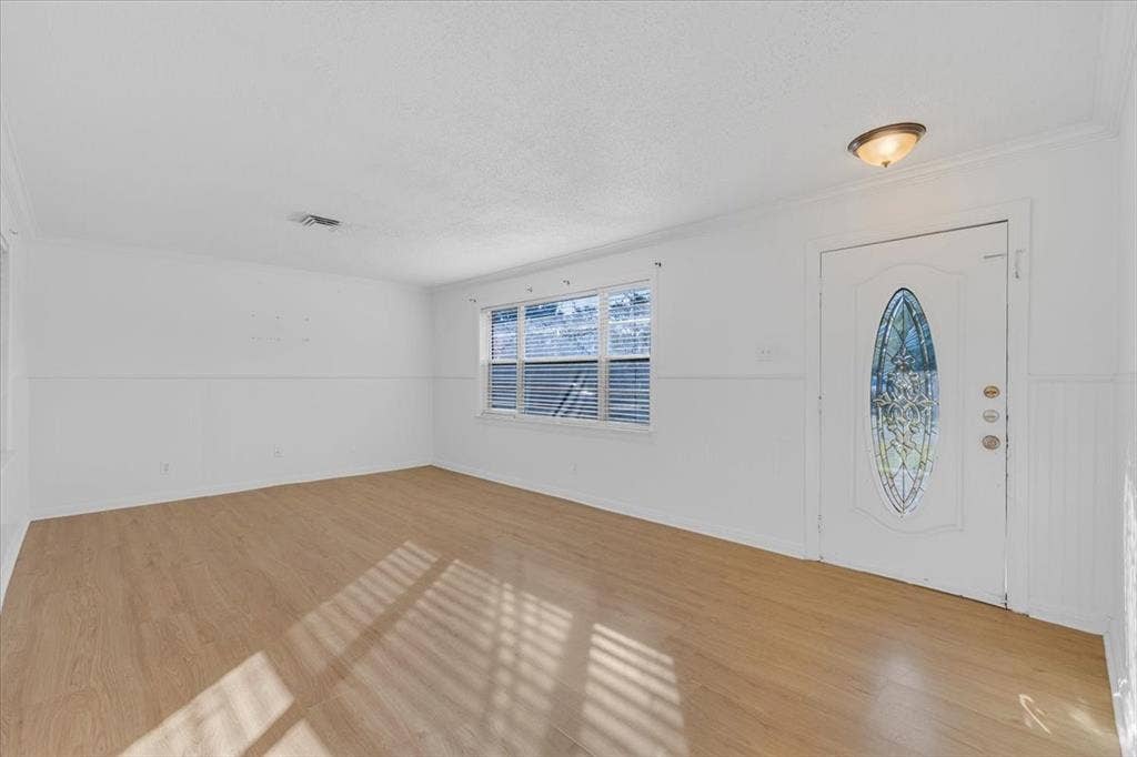 13521 Flagstone Lane, Dallas, TX 75240 Wood-finish flooring, white walls, decorative front door with an oval stained-glass insert, and a flush mount ceiling light fixture
