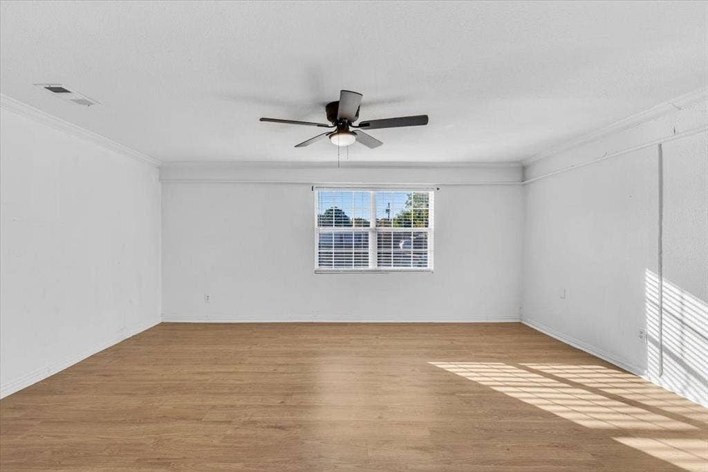 13521 Flagstone Lane, Dallas, TX 75240 Spacious room featuring wood-finish flooring, a ceiling fan, and crown molding