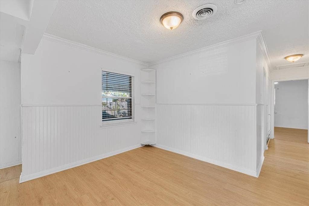 13521 Flagstone Lane, Dallas, TX 75240 Light wood-finish flooring, white beadboard wainscoting, crown molding, built-in corner shelving, and ceiling-mounted lighting fixtures