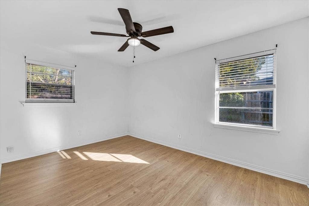 13521 Flagstone Lane, Dallas, TX 75240 Wood-finish flooring, white walls, two windows, and a ceiling fan with integrated lighting