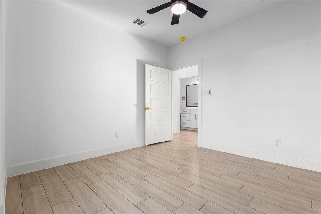 Wood-finish flooring, contemporary ceiling fan, and white five-panel interior door